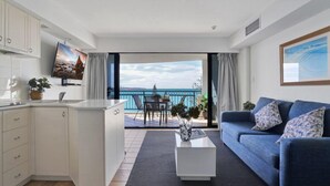 A modern living room with a sofa, coffee table, and a view of the sea.