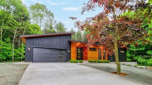 A modern house with a garage, a wooden exterior, and a gravel driveway.