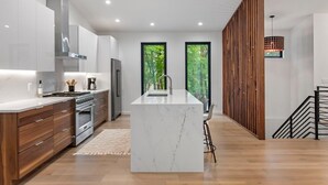 A modern kitchen with a central island, built-in appliances, and large windows.