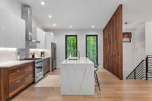 A modern kitchen with a central island, built-in appliances, and large windows.