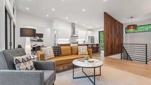 A modern living room with a sofa, coffee table, and a kitchen in the background.