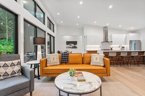 A modern living room with a sofa, a round coffee table, and a dining area with chairs.