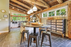 Une cuisine dotée d’un îlot central, de tabourets de bar et d’un plafond en bois.