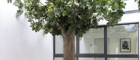 Un área de estar al aire libre con muebles de mimbre y un árbol grande.
