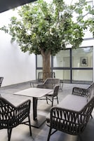 Un área de estar al aire libre con muebles de mimbre y un árbol grande.