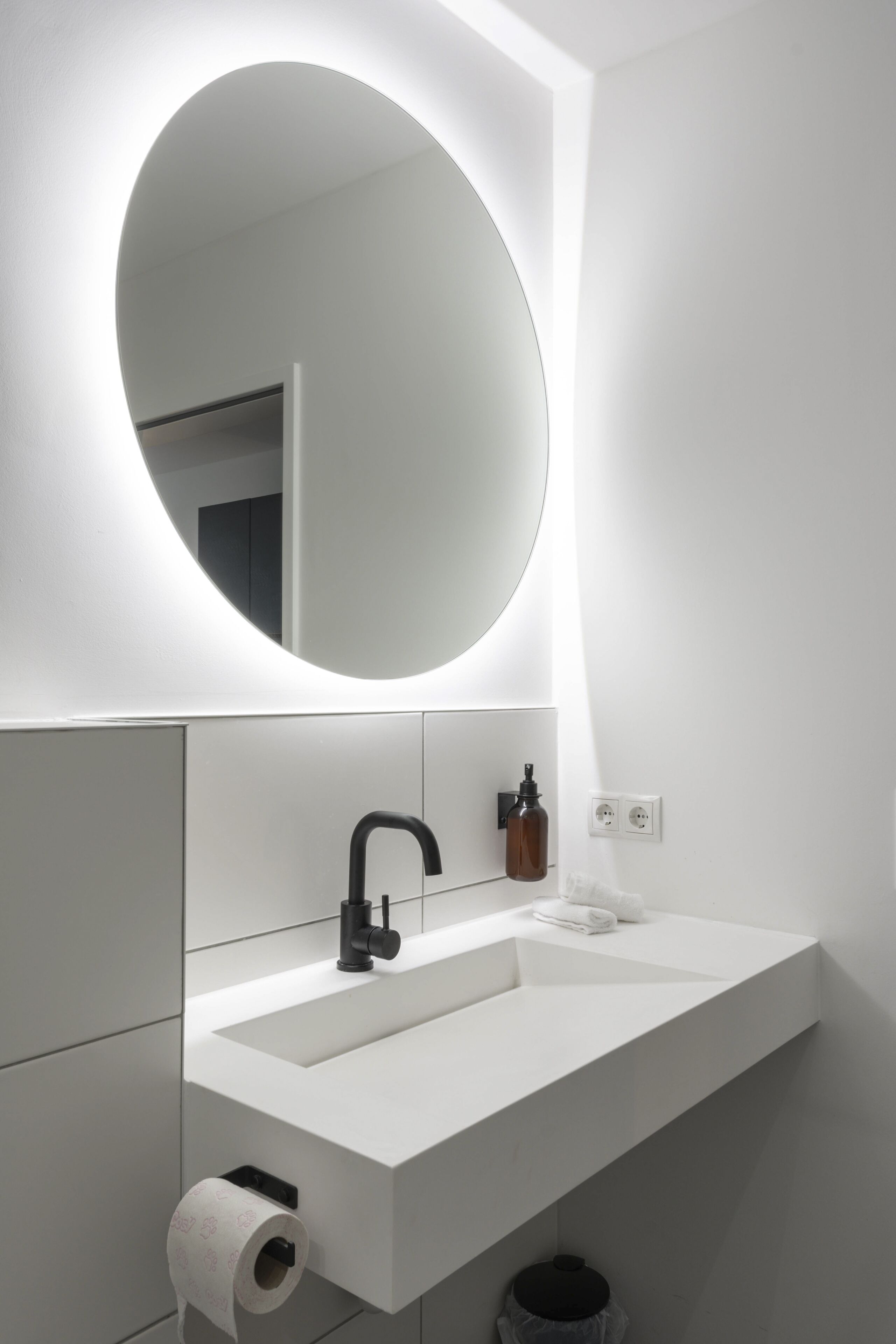 A modern bathroom with a white sink, black faucet, and a large mirror.