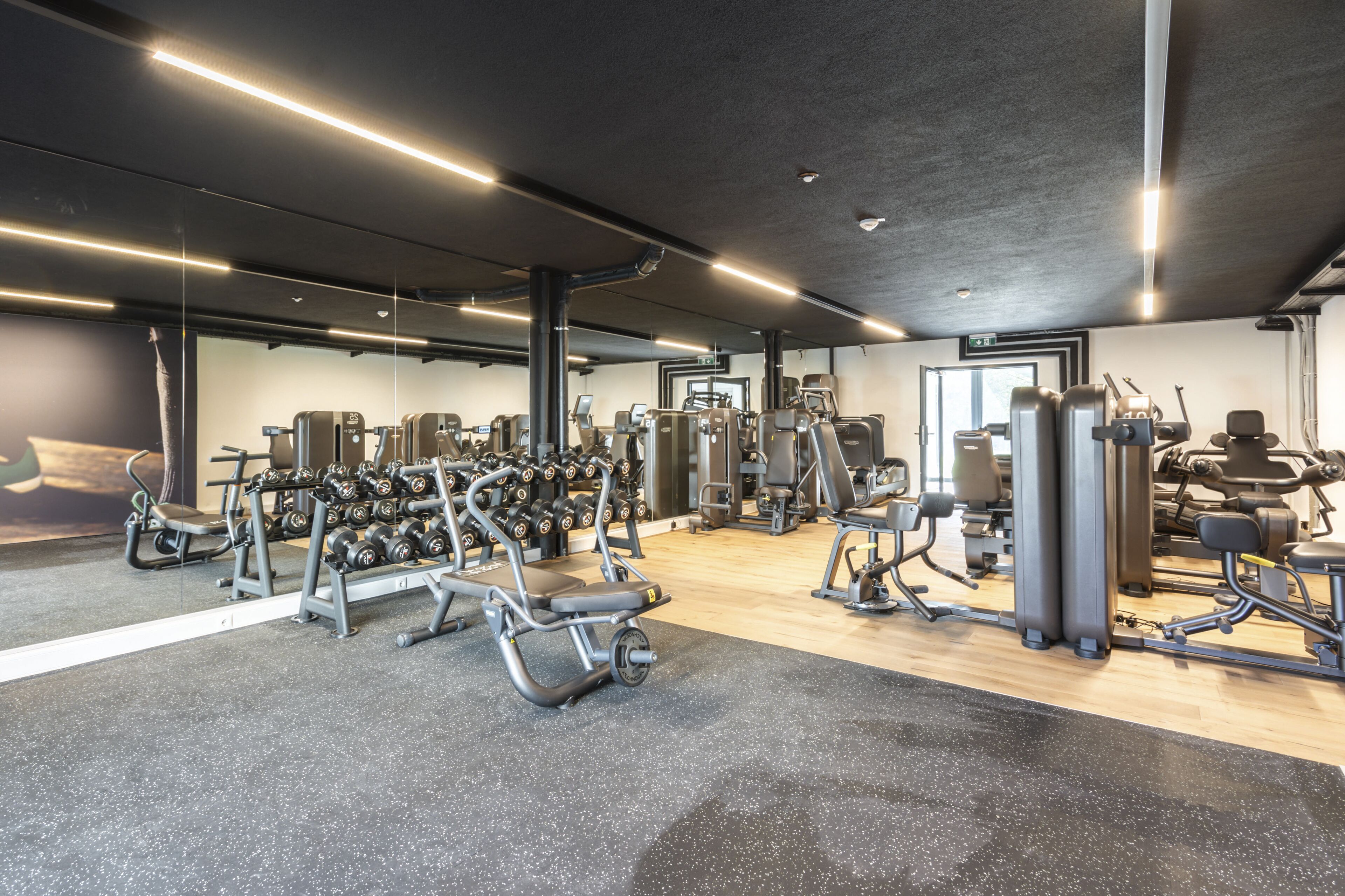 Une salle de sport moderne équipée de divers appareils d’entraînement, notamment des machines de musculation, des poids libres et des appareils de cardio.