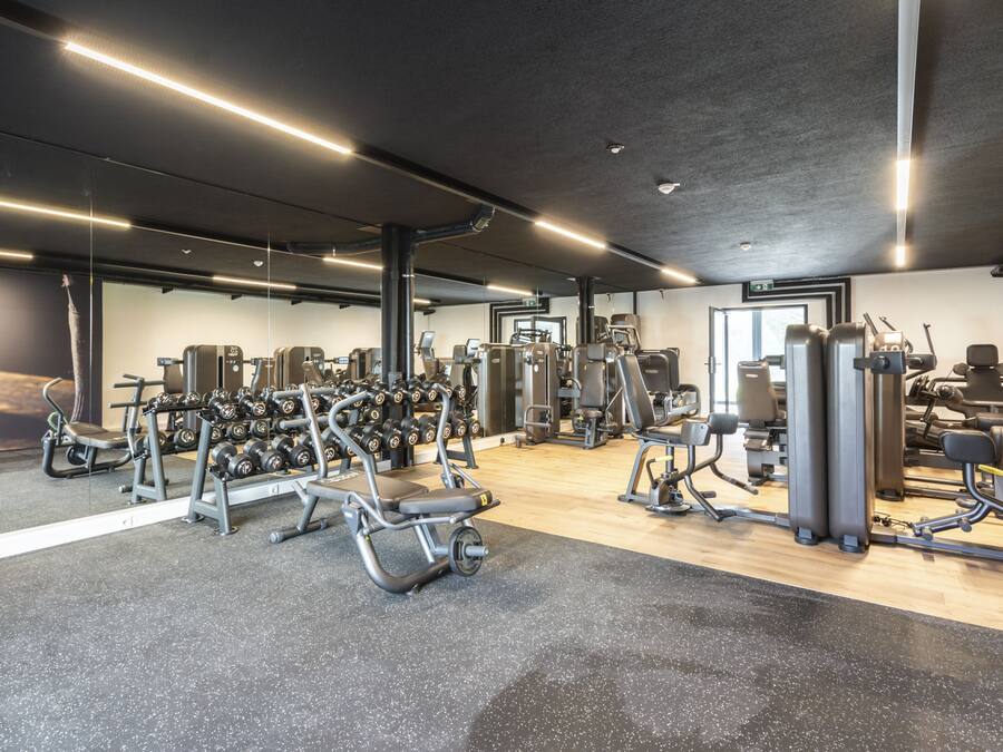 Une salle de sport moderne équipée de divers appareils d’entraînement, notamment des machines de musculation, des poids libres et des appareils de cardio.
