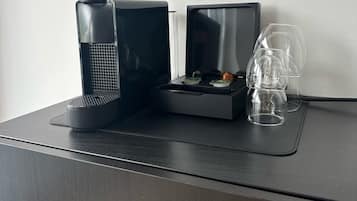 En svart kaffebryggare och en glaskanna står på ett svart bricka på ett skrivbord.