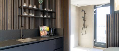 A modern kitchen with a built-in sink, a coffee machine, and a shelf with glass jars.