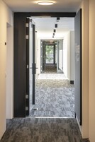 Un pasillo con piso alfombrado que conduce a una puerta con panel de vidrio.