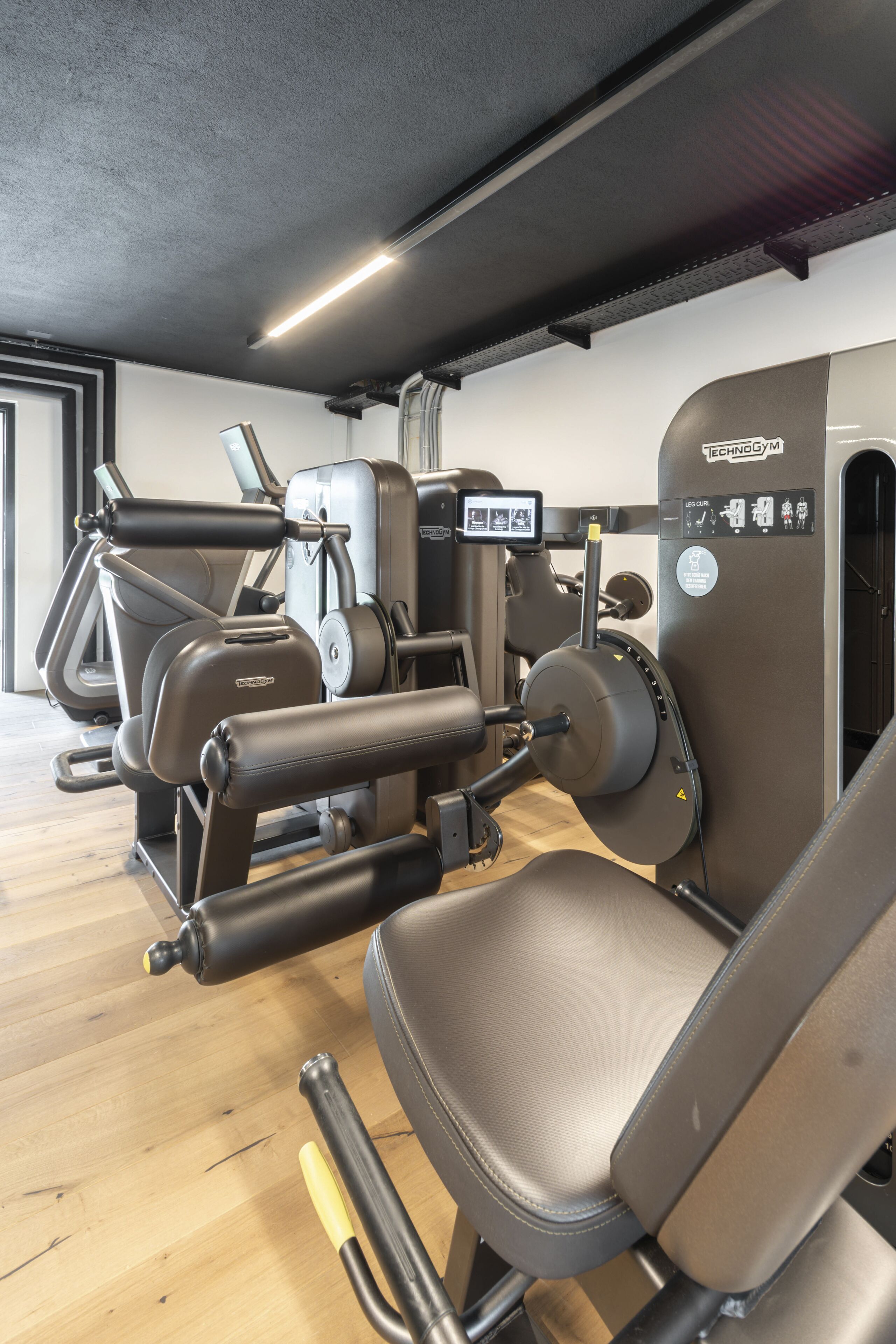 Un gimnasio con máquinas de ejercicio y suelo de madera.