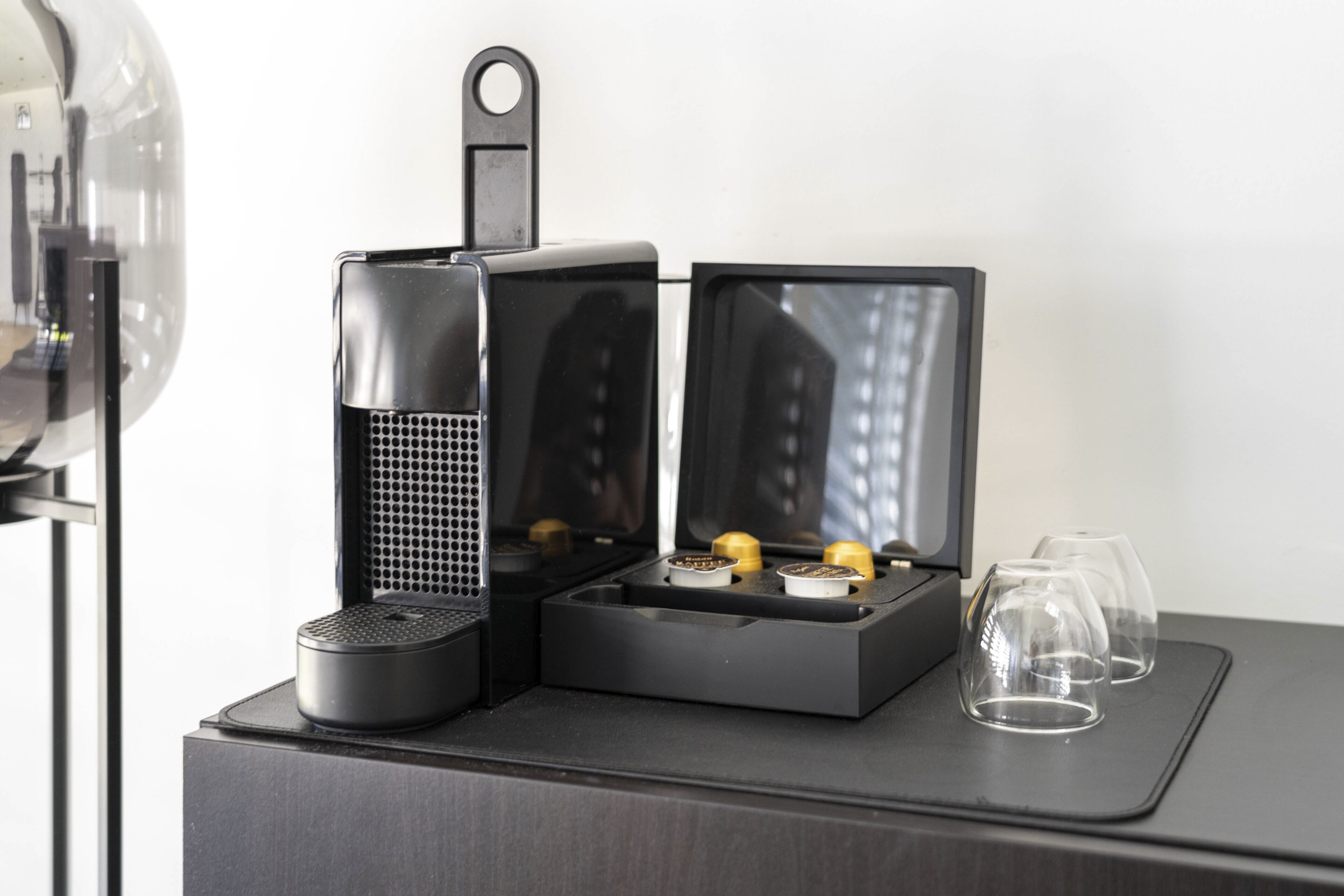 A compact coffee maker with a water reservoir and two cups on a dark surface.