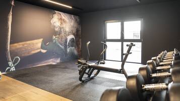 Un gimnasio con equipo de ejercicio, un ventanal grande y un mural en la pared.