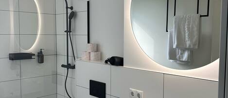 A modern bathroom with a shower, toilet, and sink.