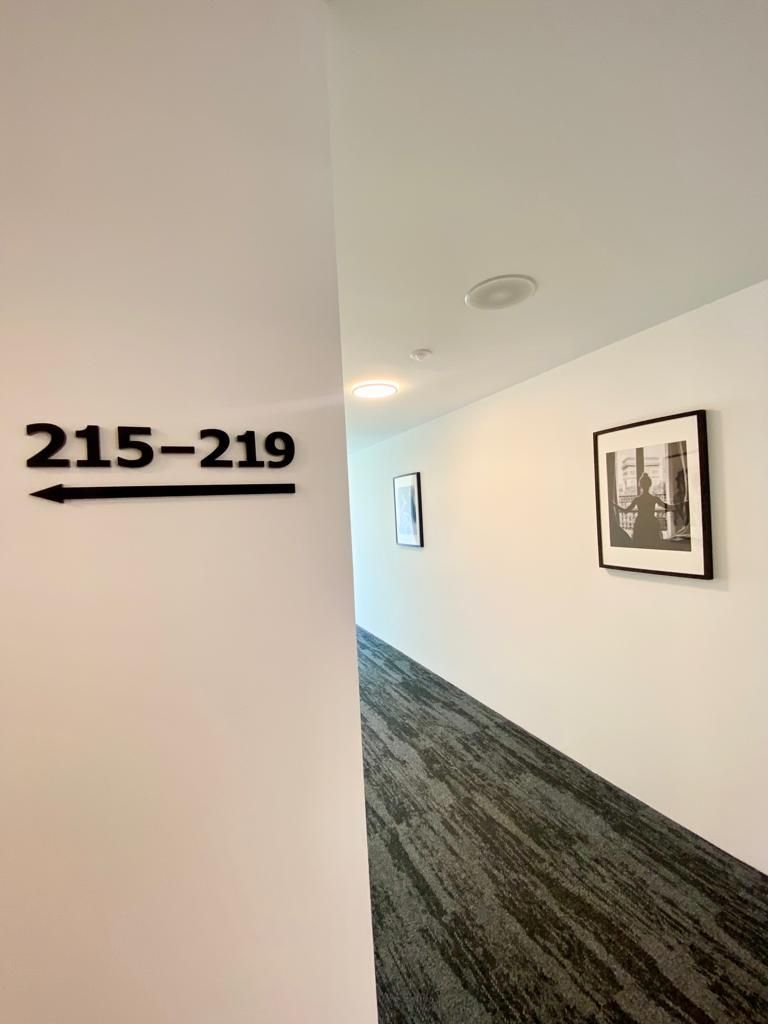 Un pasillo con un cartel indicador que muestra los números de habitación 215 a 219.