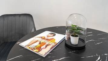 Una revista sobre una mesa de mármol negro con una cúpula de vidrio que cubre una planta en maceta.