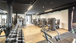 A gym with various exercise equipment, wooden flooring, and a modern design. - Village by Maier - kontaktloser Check-in (Hohenems)
