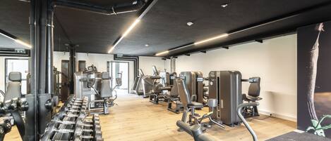 Un gimnasio con varios equipos de ejercicio, suelo de madera y un diseño moderno.
