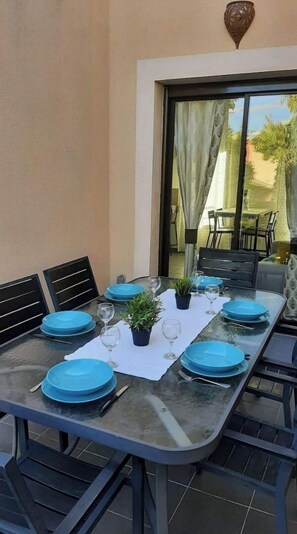 An outdoor dining area with a glass table set for six, blue plates, and wine glasses. - Toulouse charming T3 Ponts Jumeaux with terrace (Toulouse)