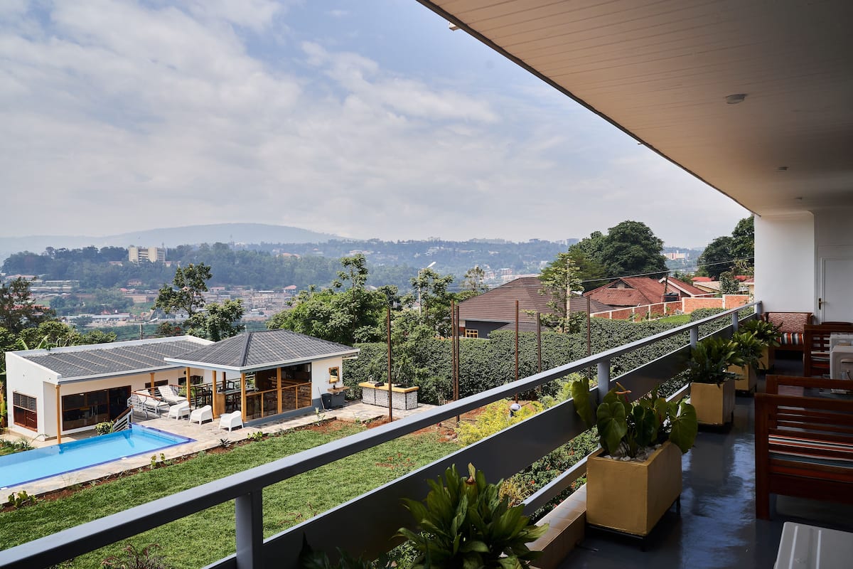 A residential property with a swimming pool, outdoor seating, and a view of a cityscape.