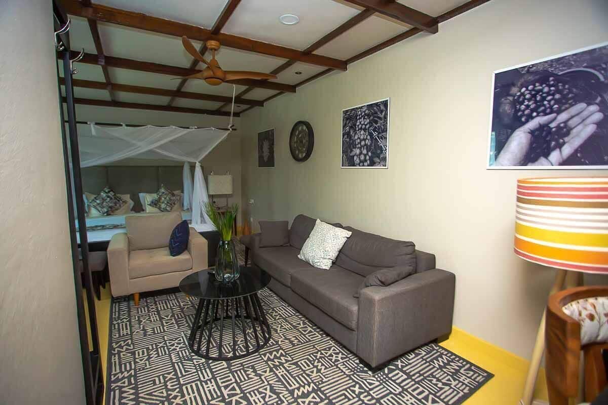 A living room with a sofa, a coffee table, a ceiling fan, and a patterned rug.