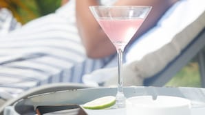 Une personne allongée sur un transat, avec une boisson devant elle.