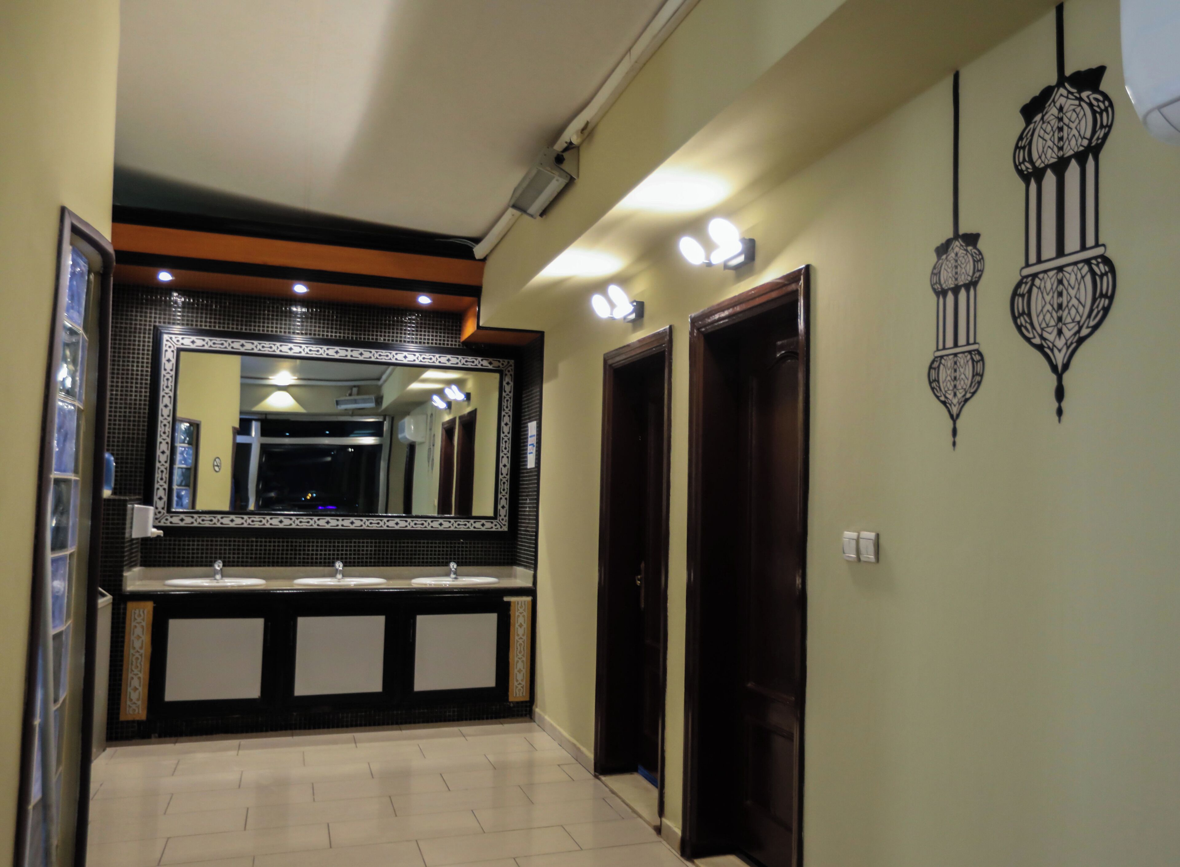 Un baño con un espejo grande, dos lavamanos y una lámpara de pared.