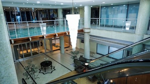 Un atrium à plusieurs niveaux, doté d’une balustrade en verre, d’une colonne centrale et d’un escalier mécanique.