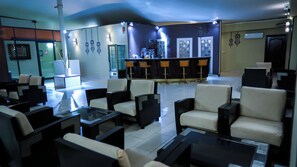 Un vestíbulo de hotel con zonas de estar, un mostrador de recepción y un bar.