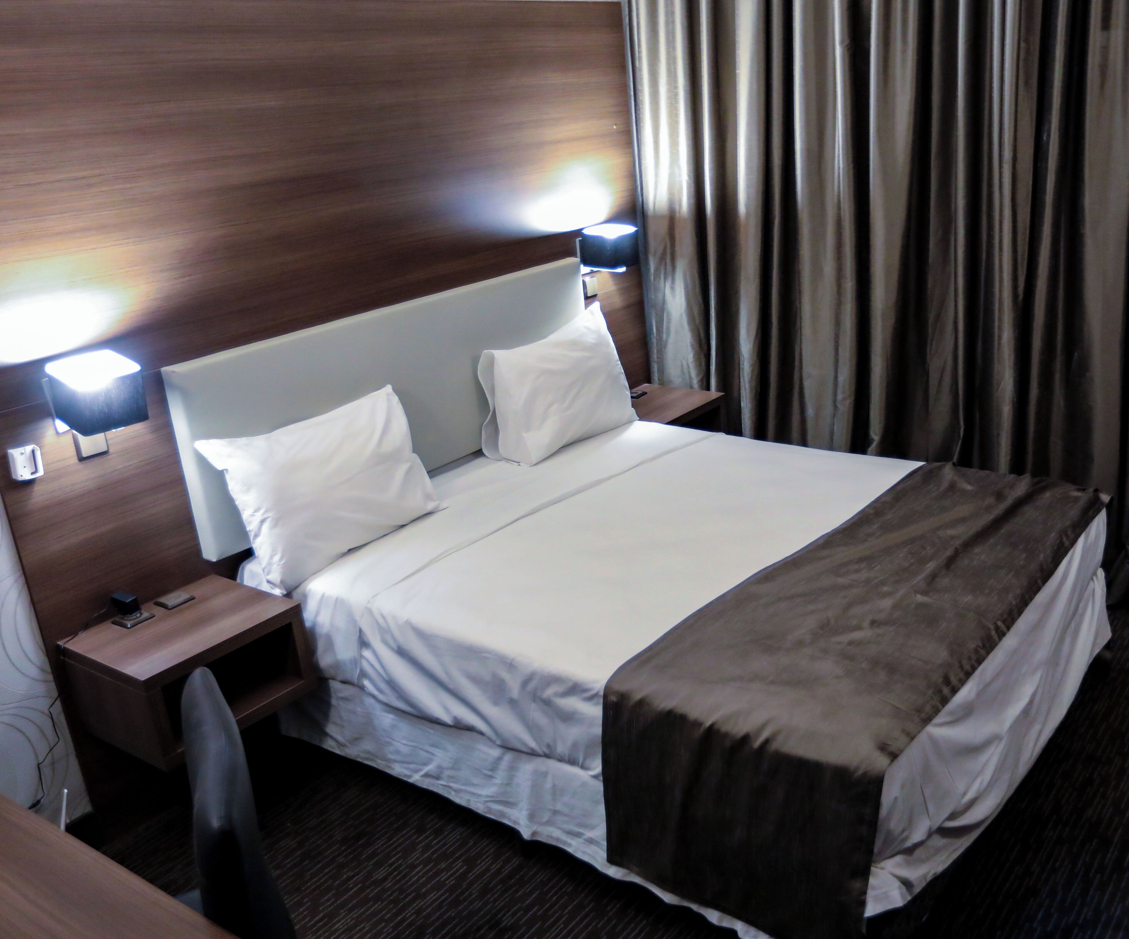 A hotel room with a large bed, two bedside tables, a desk, and a chair.