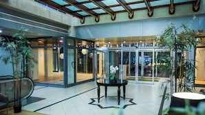 Un hall d’entrée avec une porte vitrée, une table ronde ornée d’un vase et des plantes en pot.