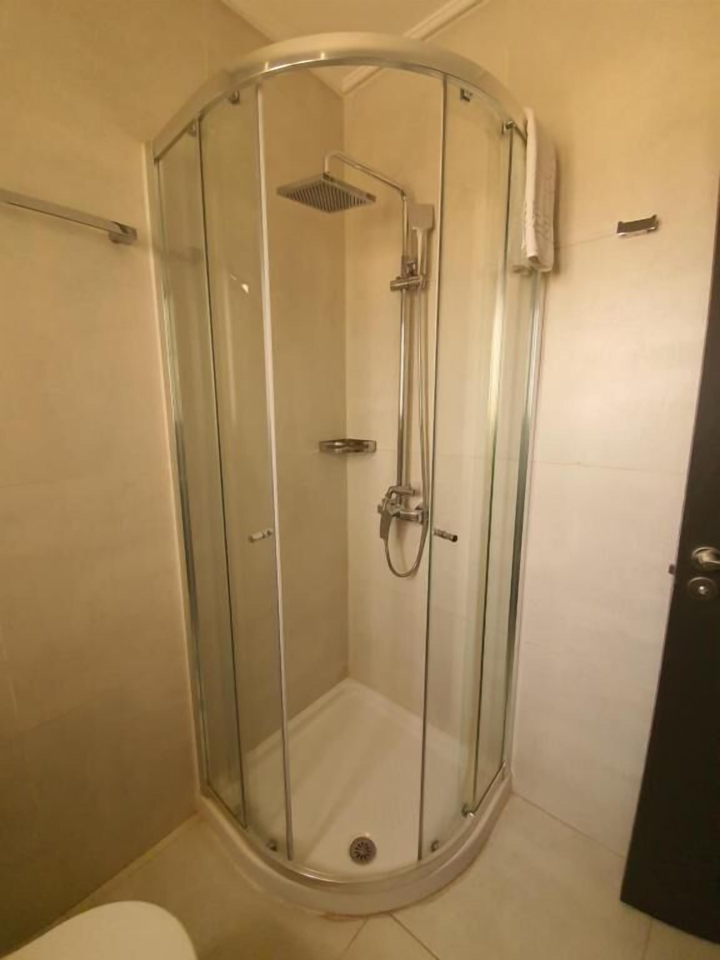 A glass-enclosed shower stall with a handheld showerhead and a fixed showerhead.