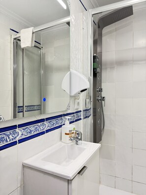 Ein Badezimmer mit Waschbecken, Spiegel und Duschbereich.
