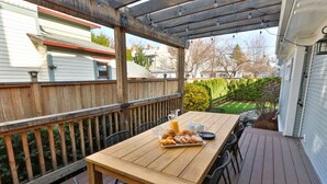 Una terraza de madera con una mesa dispuesta para el desayuno, rodeada de sillas.