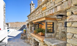 A stone building with a wooden bench, a window with a metal grill, and a stone staircase leading to a higher level.