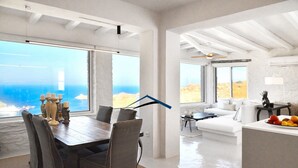 A spacious living area with a large dining table, a sofa, and a kitchen counter. - Luxurious villa with a swimming pool, sea and sunset view (Kéa)