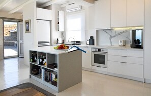 A modern kitchen with white cabinetry, a built-in oven, and a marble backsplash.