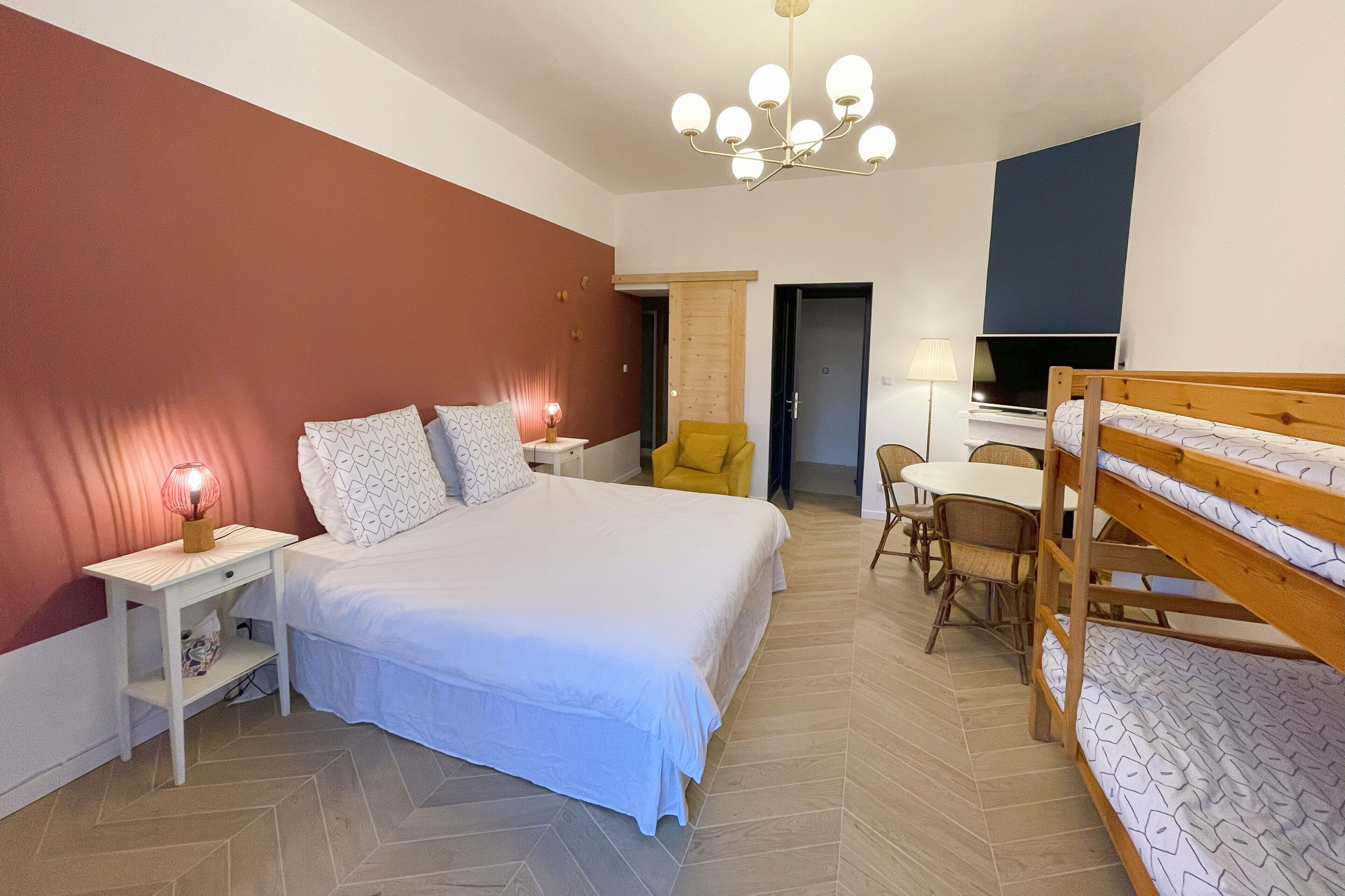 Ein Schlafzimmer mit Bett, Nachttischen, einem Sessel, einem Etagenbett, einem Schreibtisch und einem Fernseher.