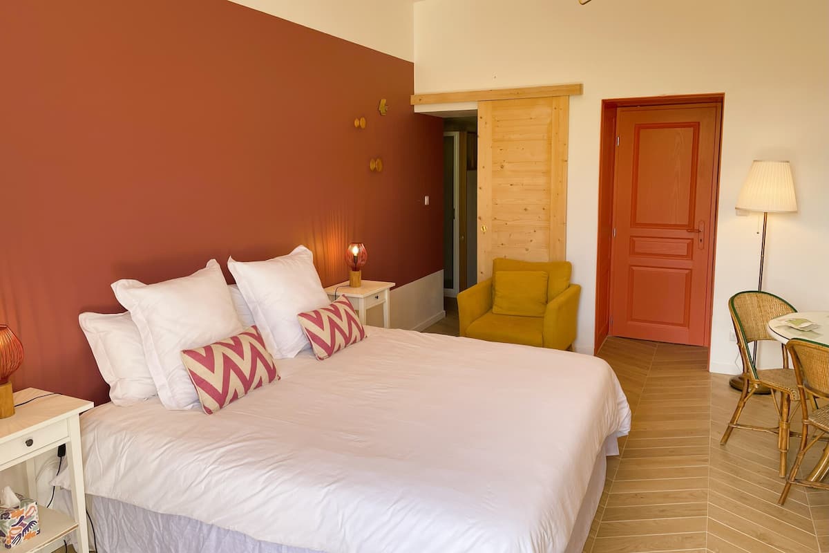A bedroom with a bed, bedside table, lamp, chair, and a door.