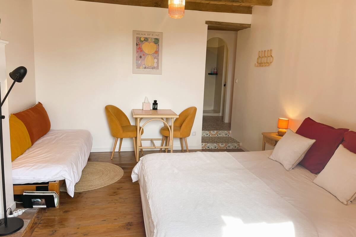A bedroom with two beds, a small table, and chairs.