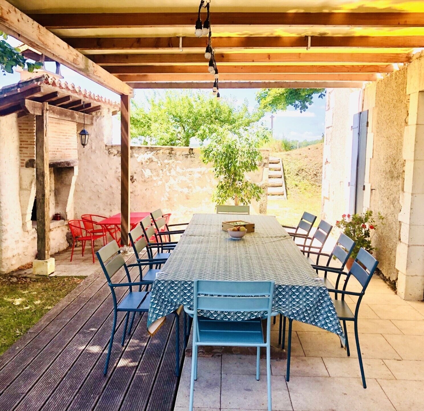 An outdoor patio with a table and chairs, a hanging light fixture, and a brick wall.