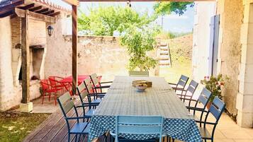 An outdoor patio with a table and chairs, a hanging light fixture, and a brick wall.