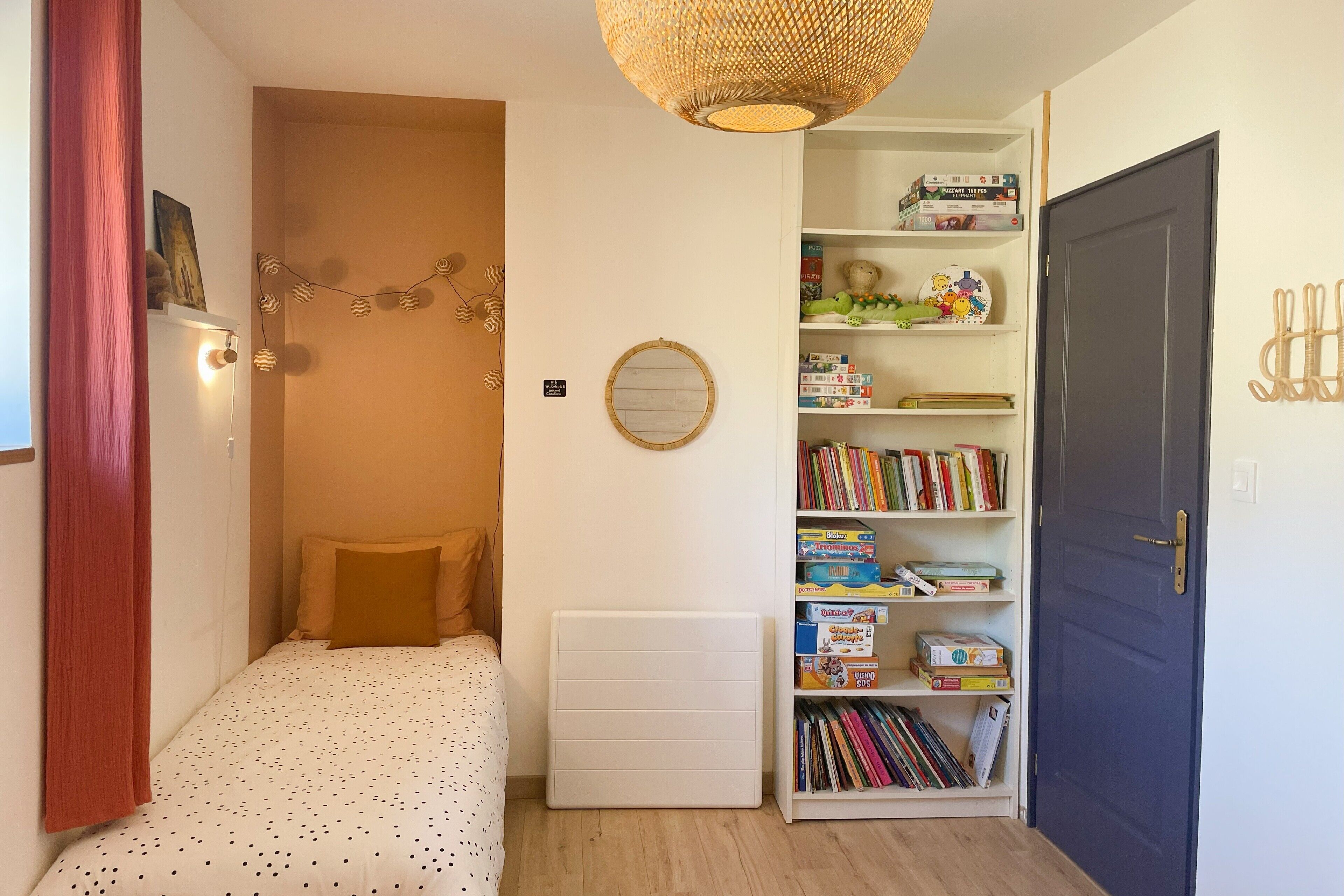 Un dormitorio con cama, un radiador, una estantería y una puerta.