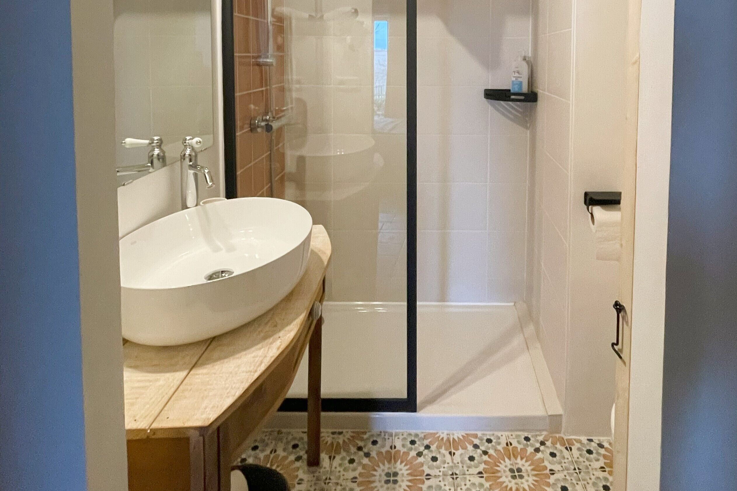 A bathroom with a large white sink, a glass shower enclosure, and a tiled floor.
