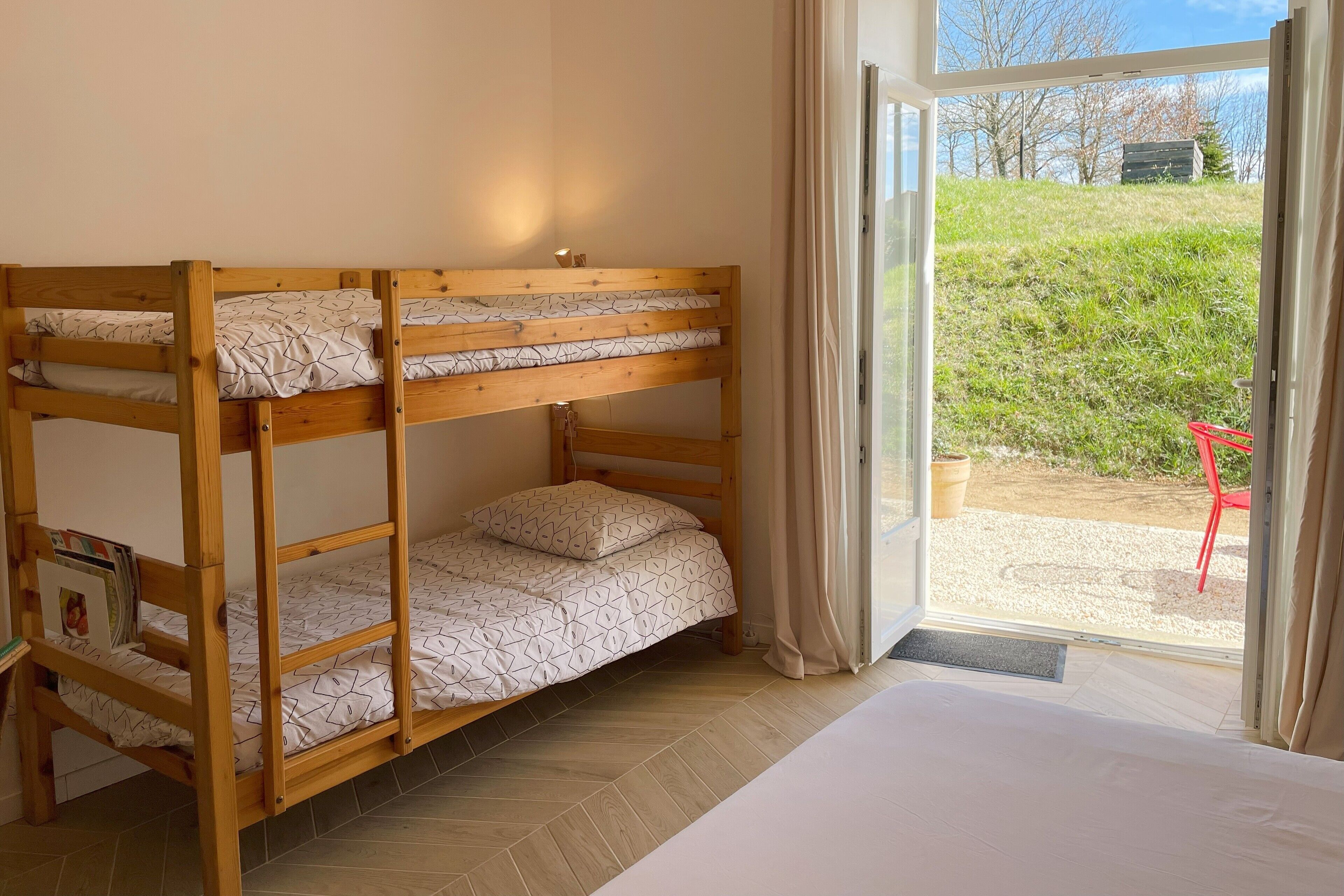 A bunk bed room with a view of a grassy area and trees outside.