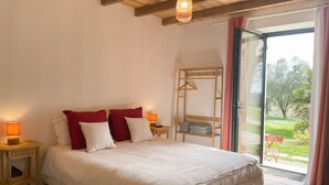 A bedroom with a large bed, wooden headboard, and a view of a garden through a sliding glass door.