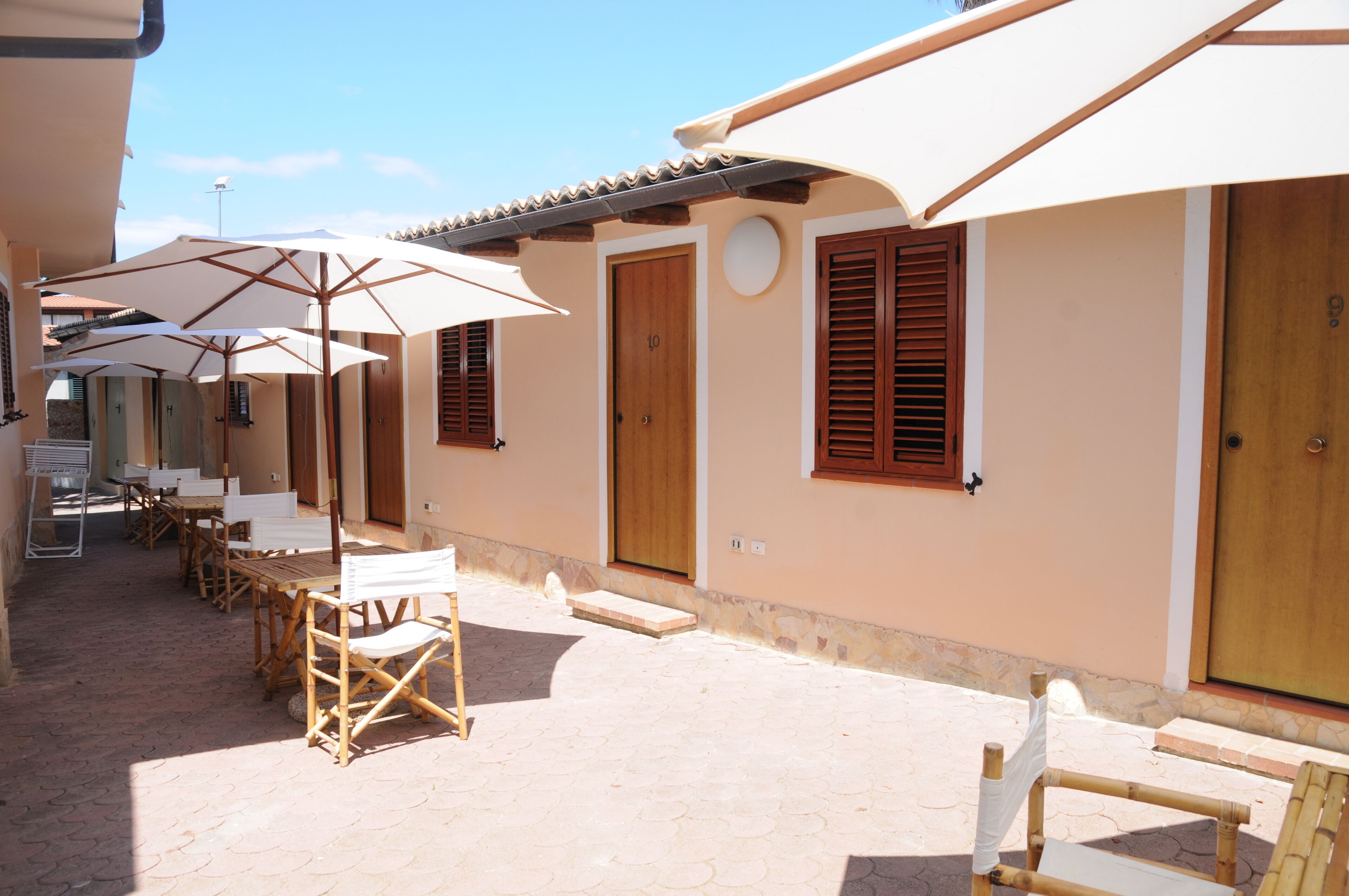 Un patio con mobiliario exterior, sombrillas y puertas de madera.