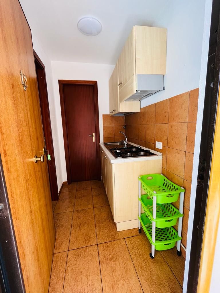 Une petite cuisine équipée d’une cuisinière, de placards et d’un panier vert.