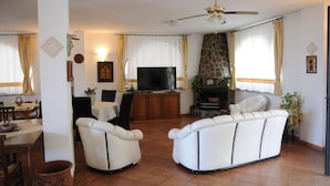 A living room with a sofa, television, fireplace, and dining area. - Residence Villa Grazia  (Ricadi)